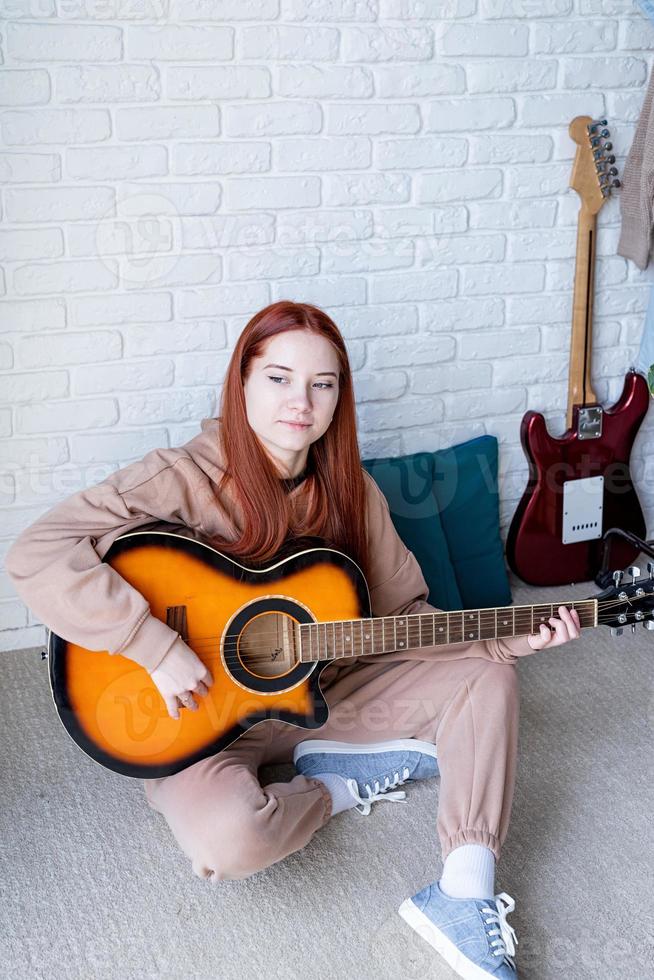 Young woman playing guitar at home photo