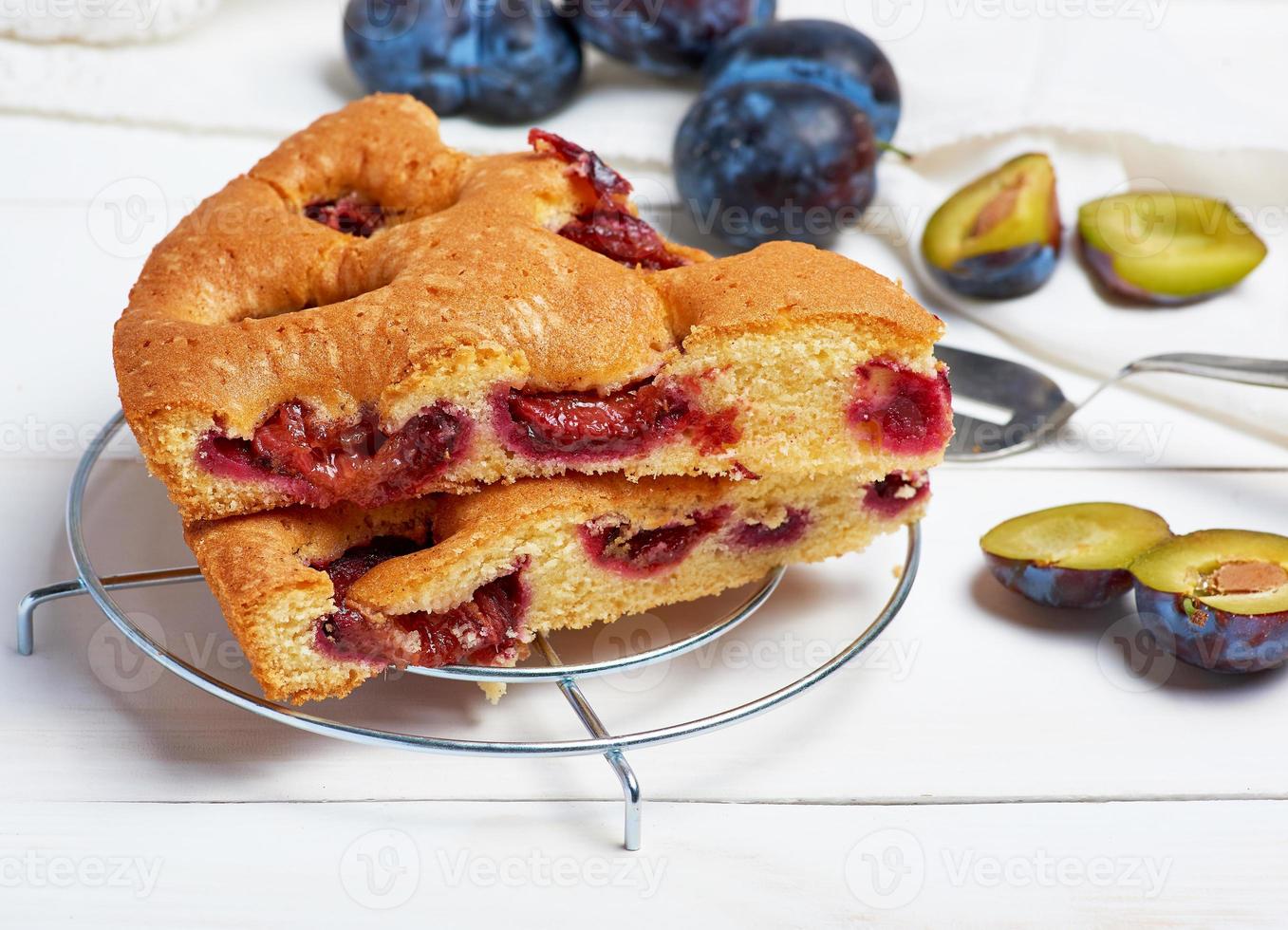 slices of biscuit plum cake on a white wooden board and fresh fruits photo