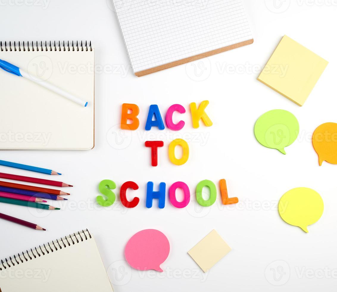 inscription back to school from multi-colored plastic letters and a stack of notebooks photo