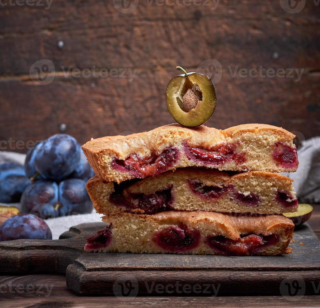 stack of triangular slices of sponge cake with blue plums photo