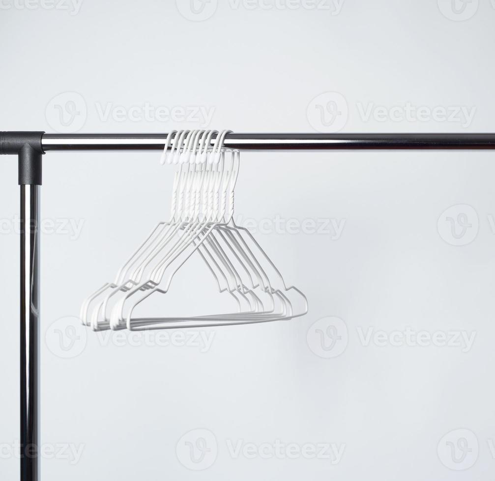 empty white metal hangers hang on a chrome bar photo
