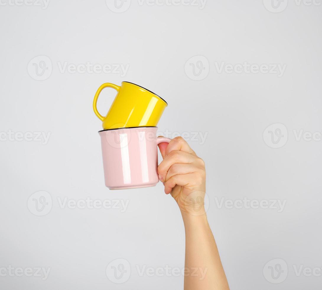 female hand holding a stack of ceramic mugs photo