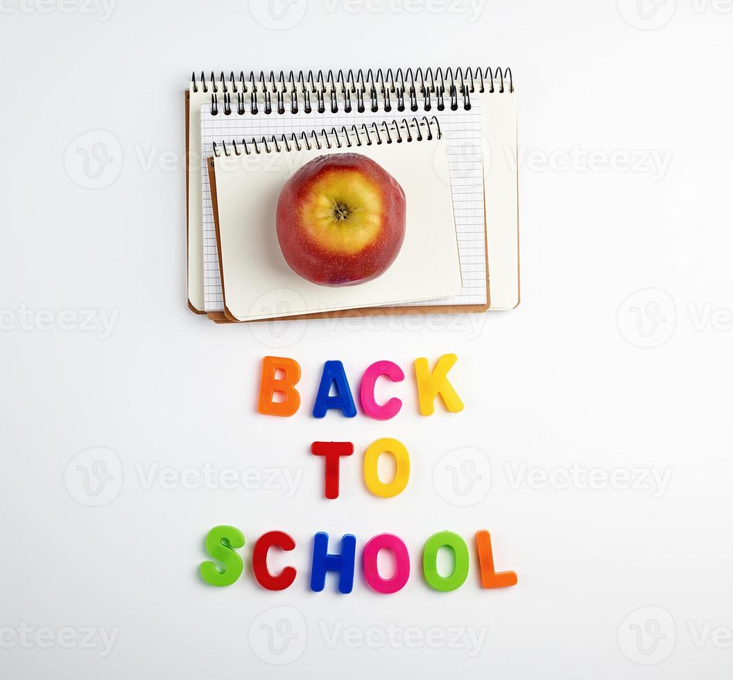 inscription back to school from multi-colored plastic letters and a stack of notebooks photo