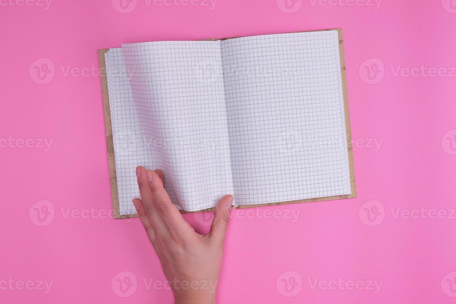 empty open notebook in a cell and a female hand photo