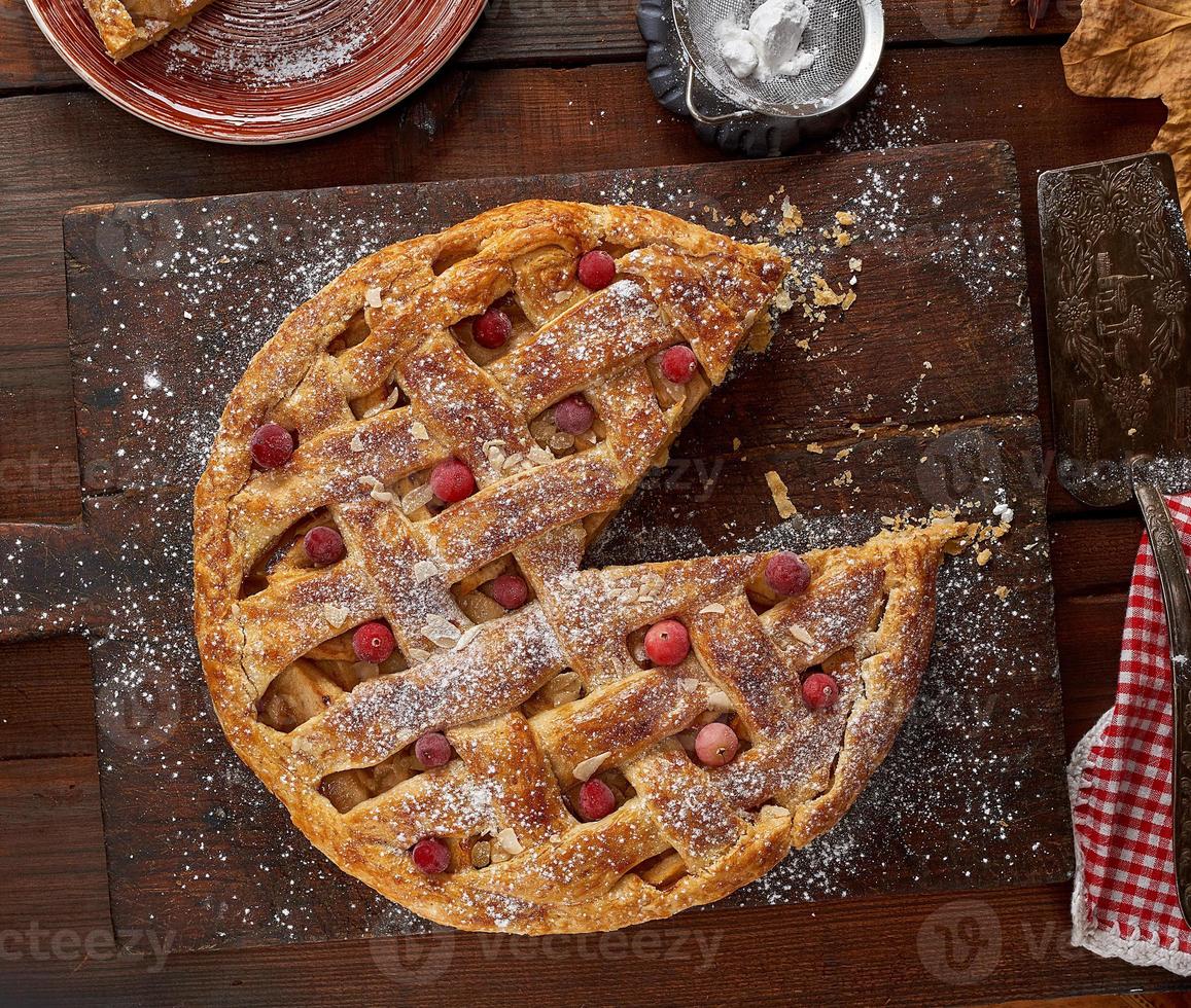 round apple pie on a rectangular old brown cutting board sprinkled with powdered sugar photo
