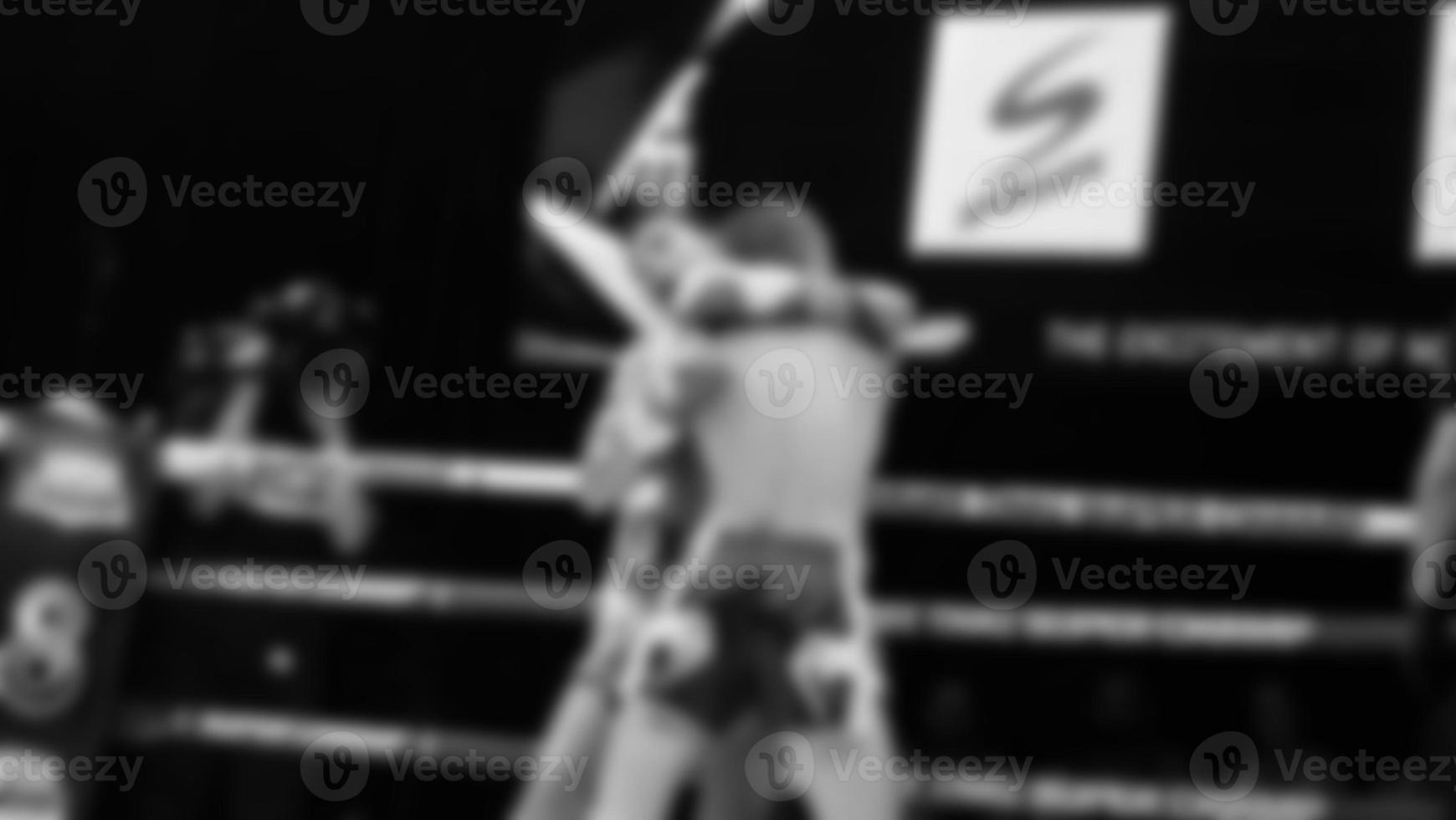 Blurred images black and white photo style of Thai boxing or Muay Thai or Kickboxing which local and foriegn boxer are fighting on the ring at indoor stage as martial art sport. Muay Thai Kick boxing