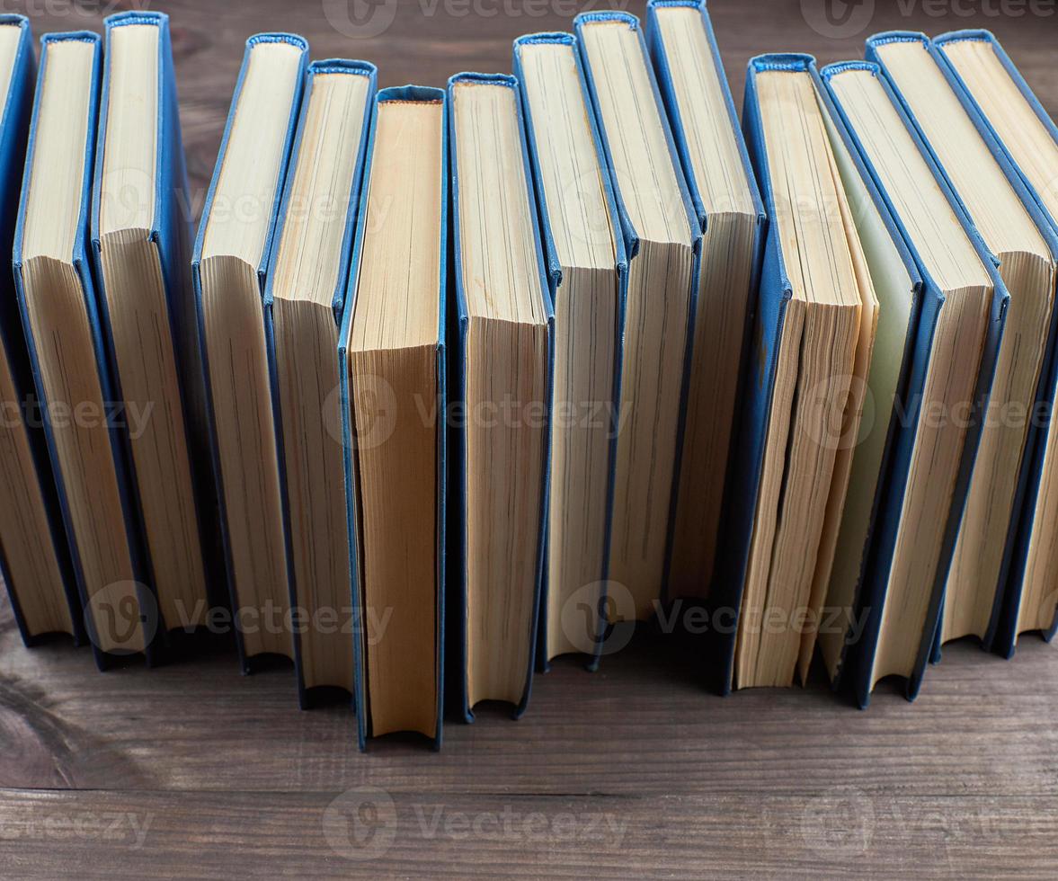stack of books in a blue cover on a brown wooden table photo