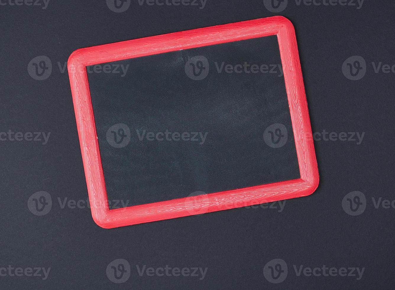 empty chalk board in red frame on black background photo