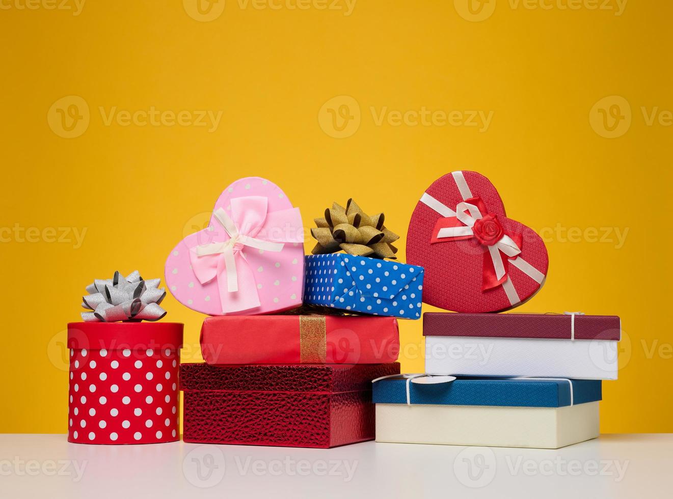 A stack of gift boxes wrapped in colorful paper on a yellow background. Happy Holidays photo