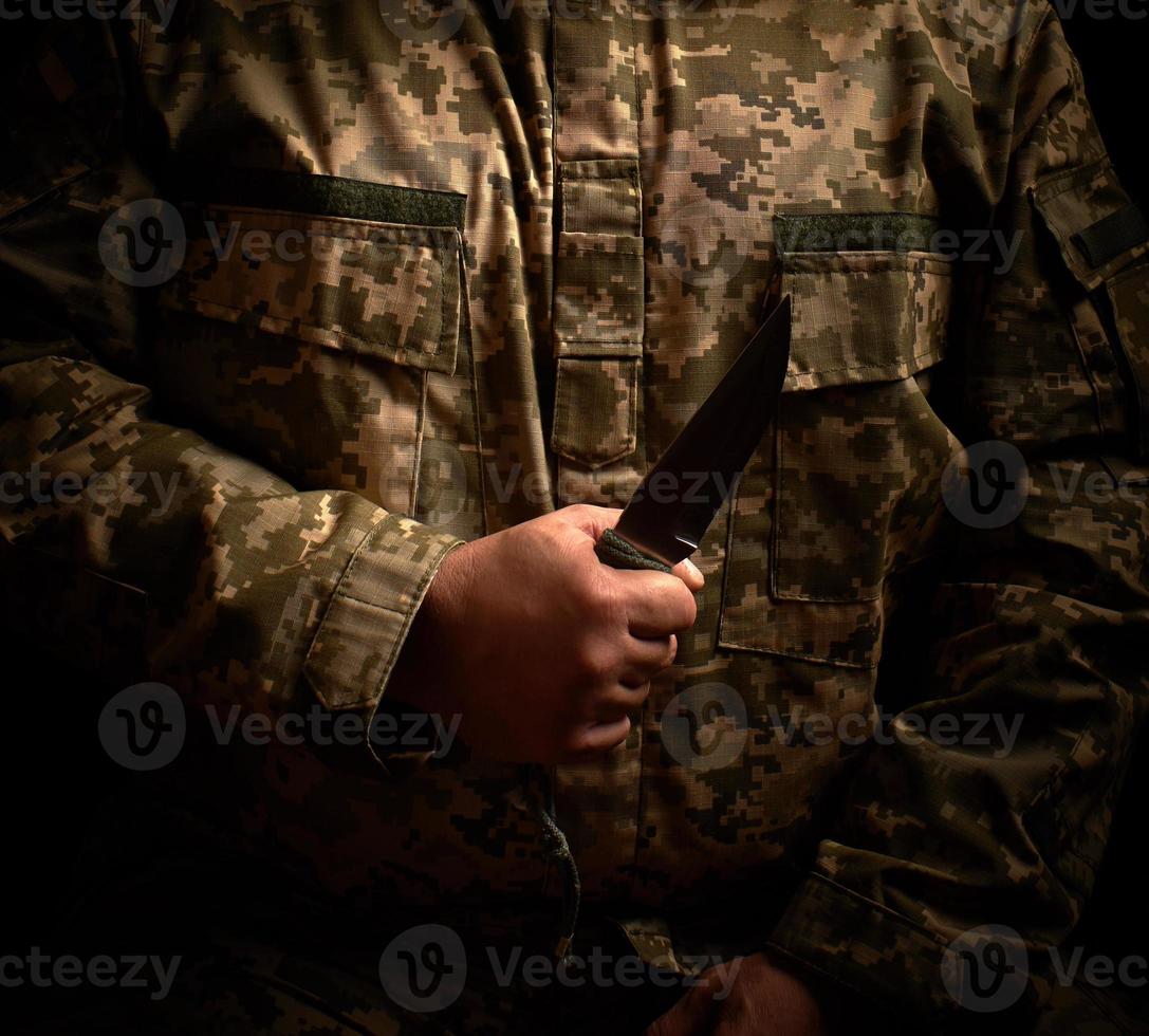 soldado vestido con uniforme militar sostiene un cuchillo táctico afilado foto