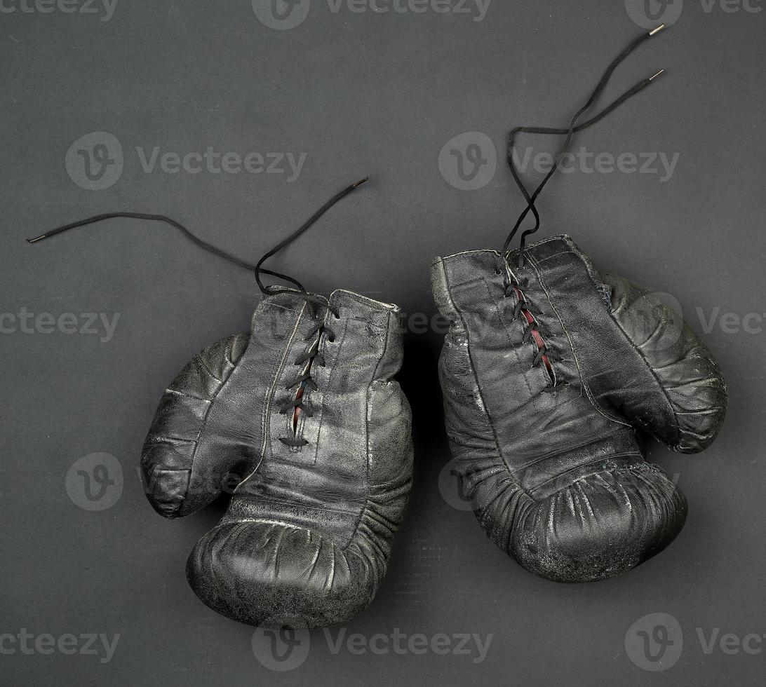 pair of black leather very old boxing gloves on a black background photo