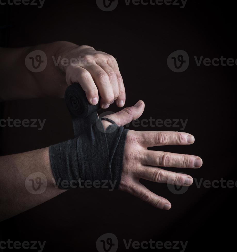 man wraps his hands in black textile bandage photo