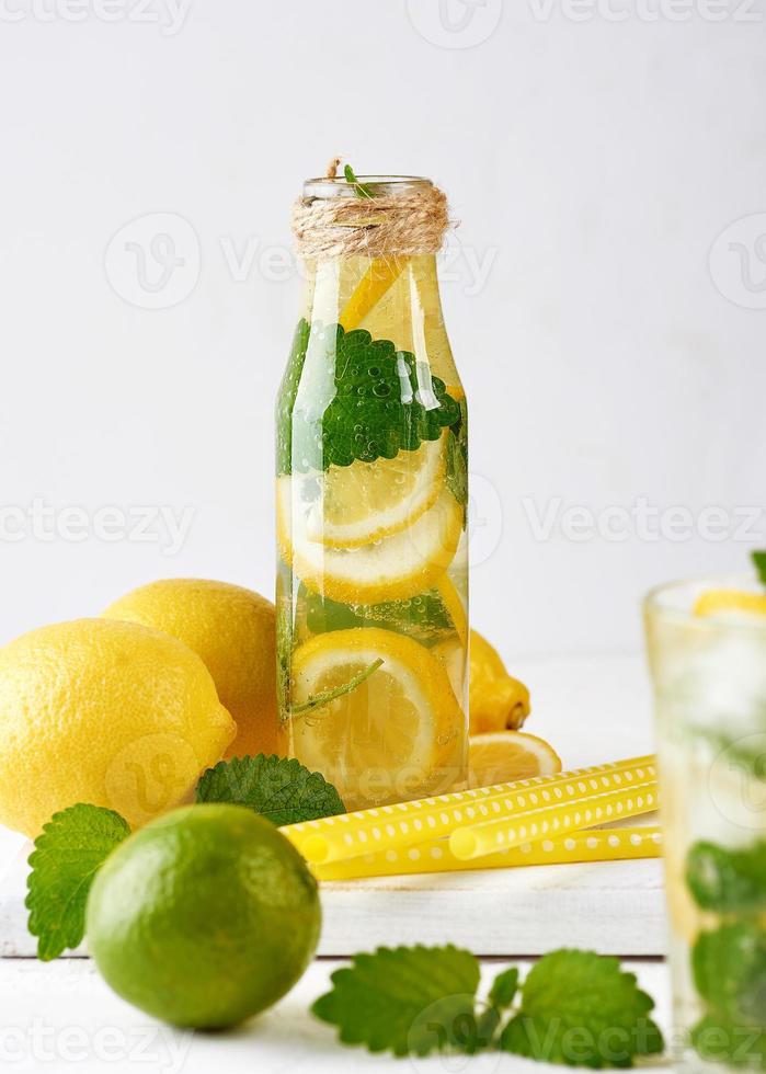 summer refreshing drink lemonade with lemons, mint leaves, lime in a glass bottle photo