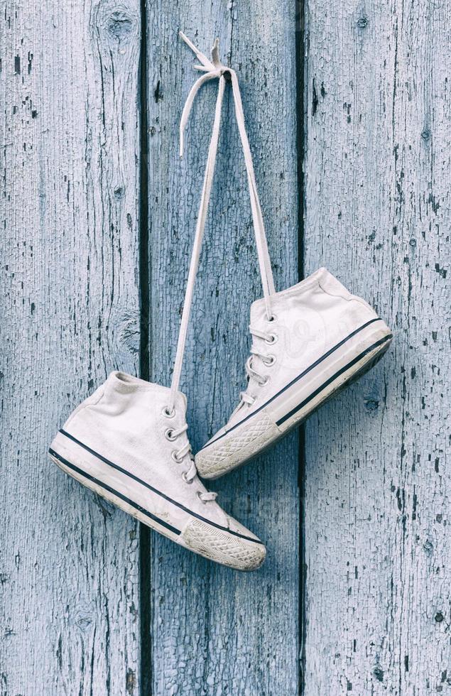 pair of white old textile sneakers hanging photo