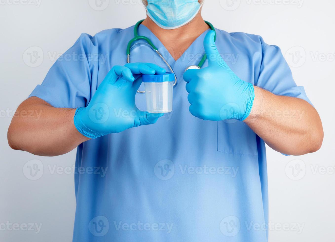 doctor in blue uniform and latex gloves is holding an empty plastic container for taking urine samples photo