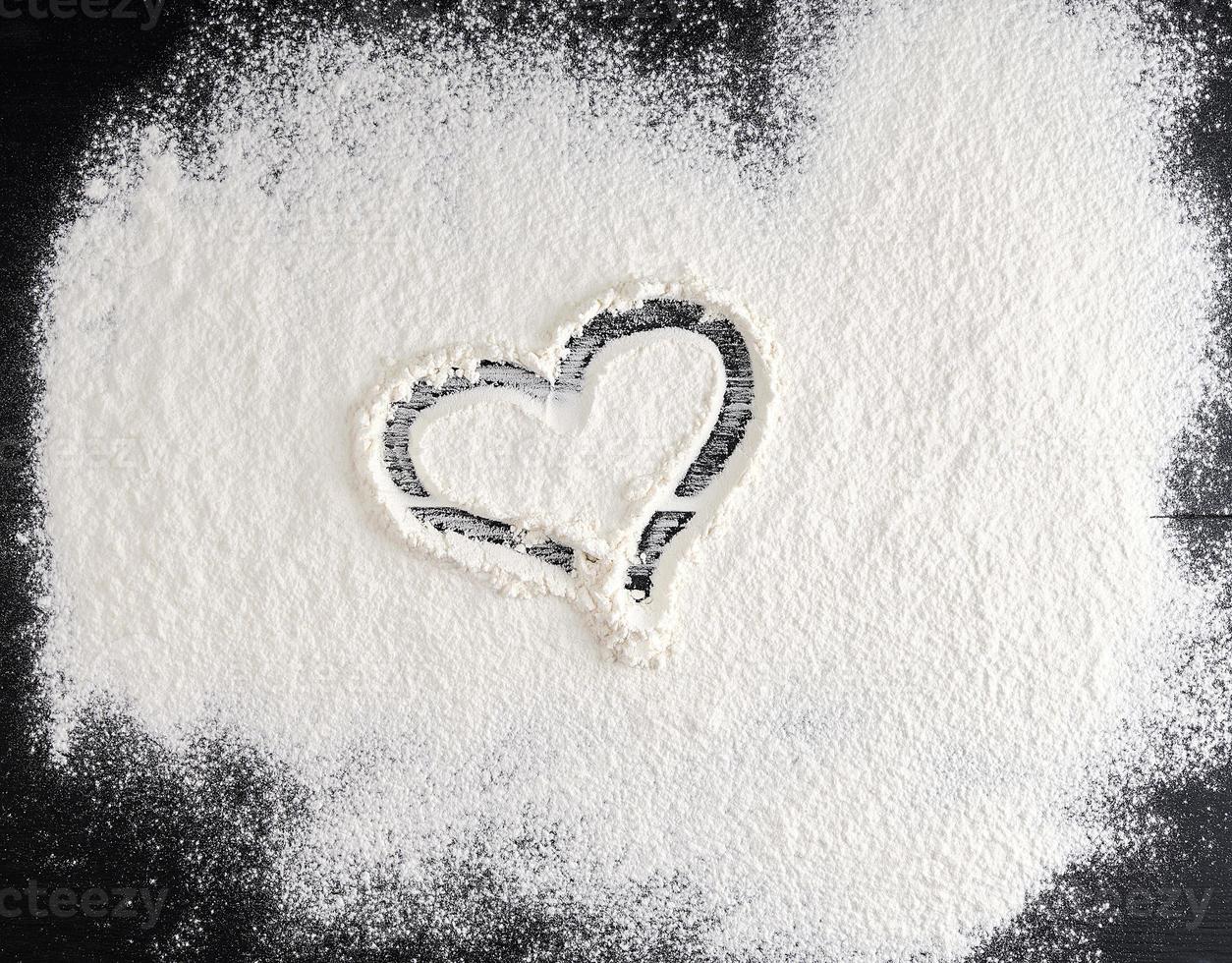 sprinkled white flour on the black table, top view photo