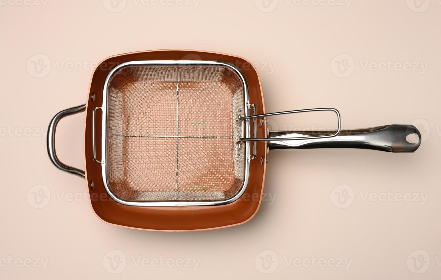 empty copper deep frying pan with grill grate on beige background. View from above photo