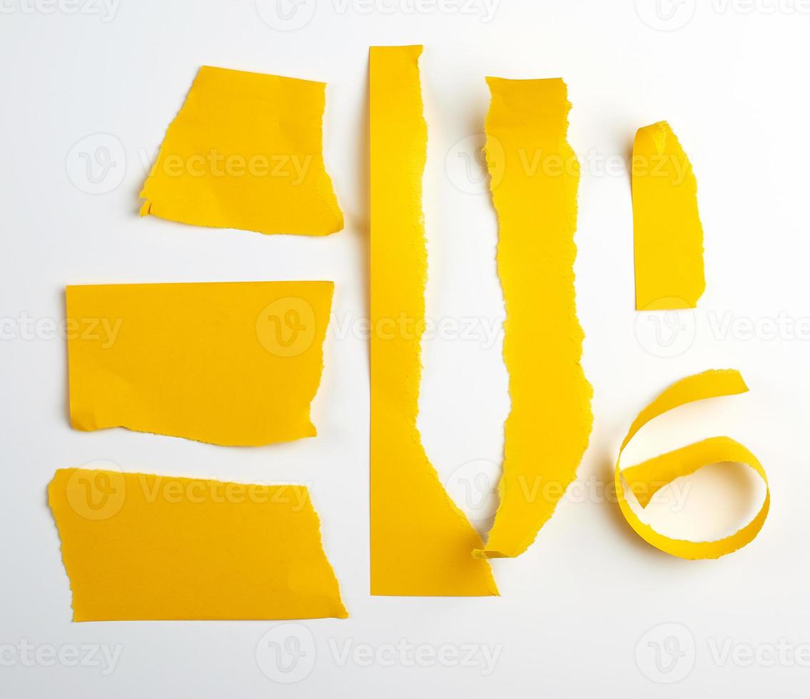 various torn strips of yellow paper on a white background photo