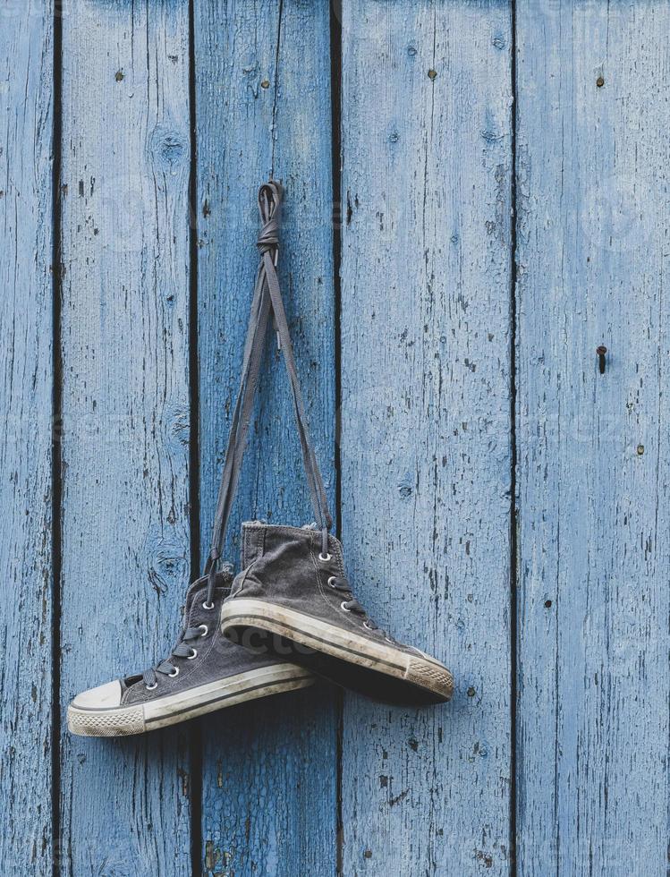 very old textile sneakers hanging on a nail photo