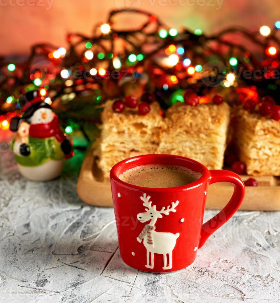 red ceramic cup with black coffee. near green branches of spruce and christmas toys photo