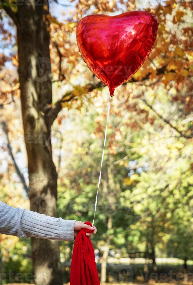 female hand holding a red balloon photo