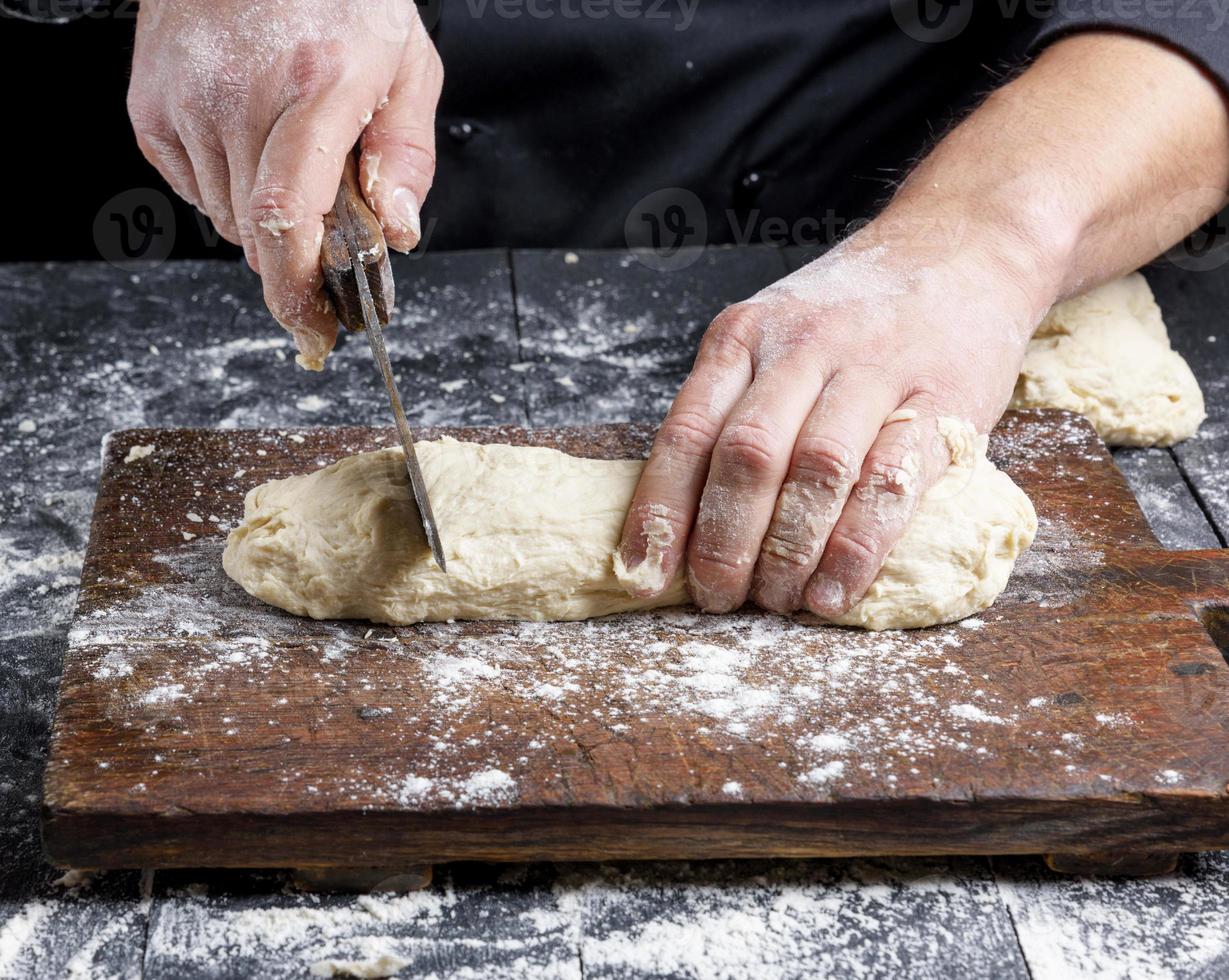 el chef corta la masa de harina de trigo blanco en trozos foto
