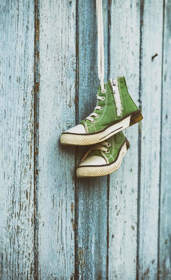par de zapatillas clásicas verdes muy viejas colgando de encaje blanco foto