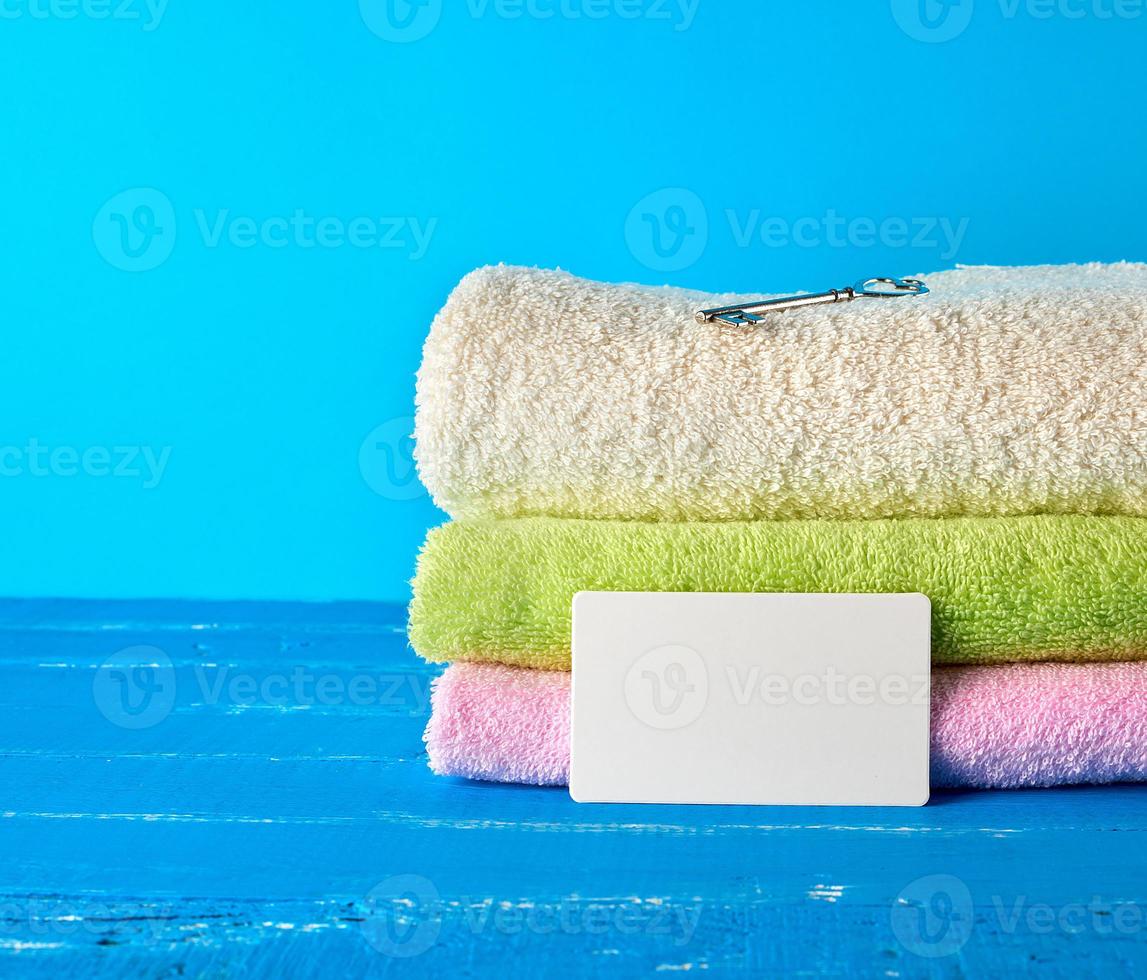 three multi-colored new terry bath towels folded on a blue wooden background photo