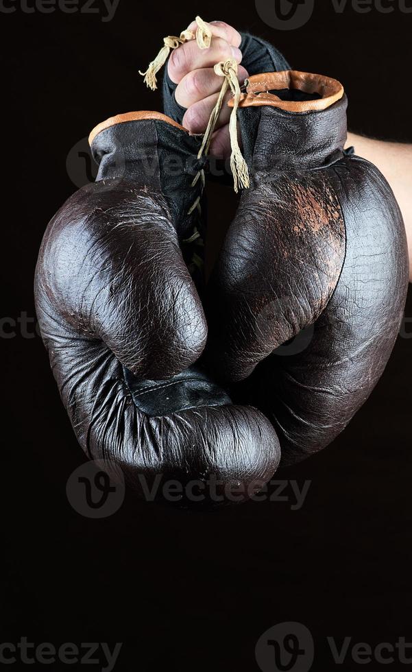 hand holds a pair of old leather brown boxing gloves photo