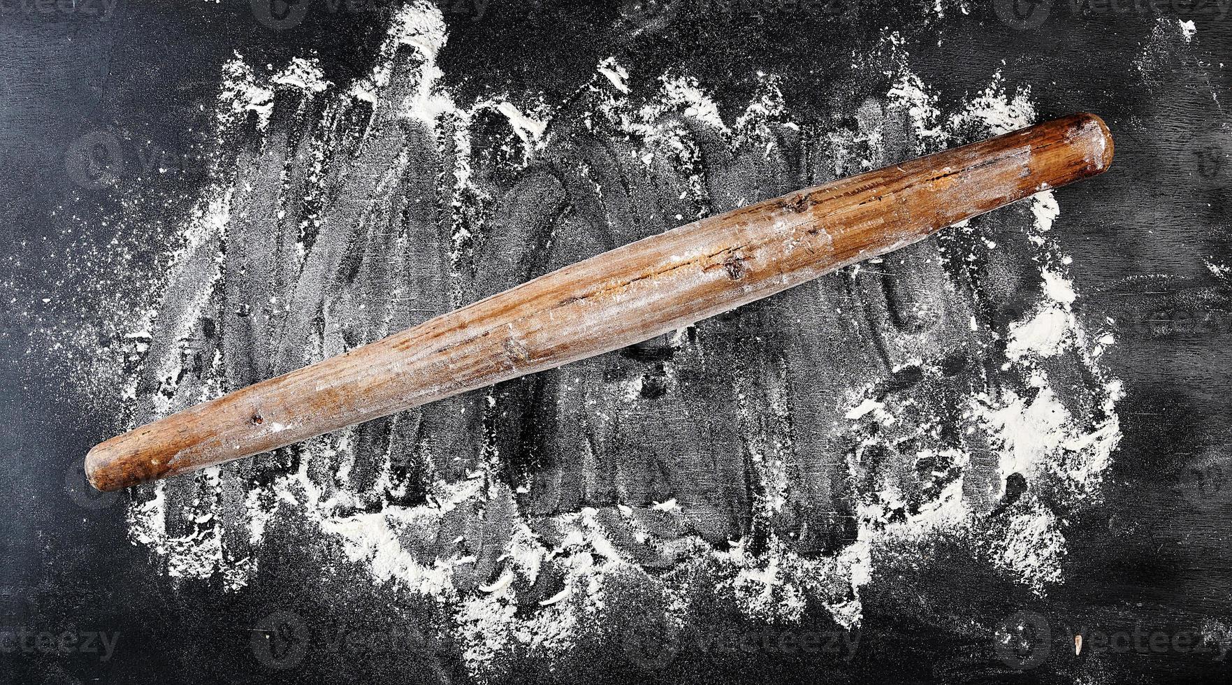 very old wooden rolling pin on a black background photo