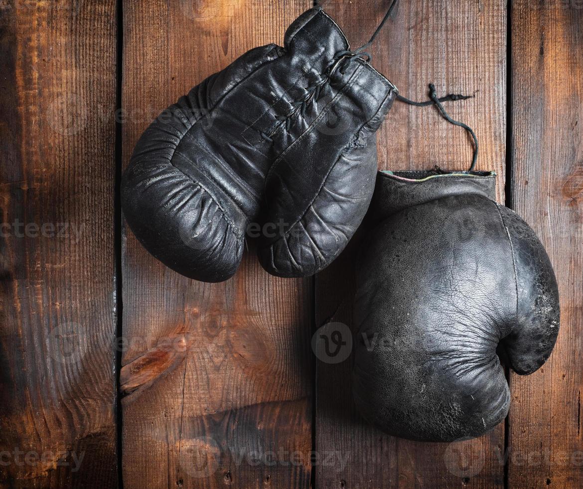 very old black boxing gloves on a brown wooden background photo