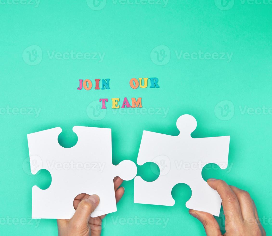 women hand hold  large white puzzles and the inscription join our team photo