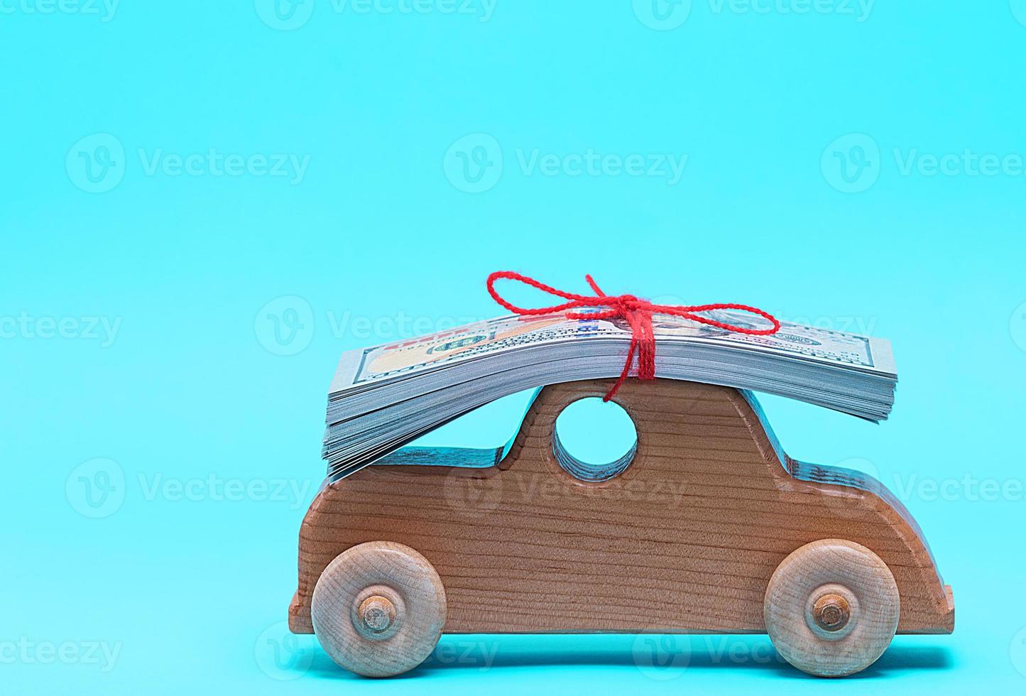 pequeño coche de madera para niños lleva en la parte superior del techo una pila de billetes de papel foto