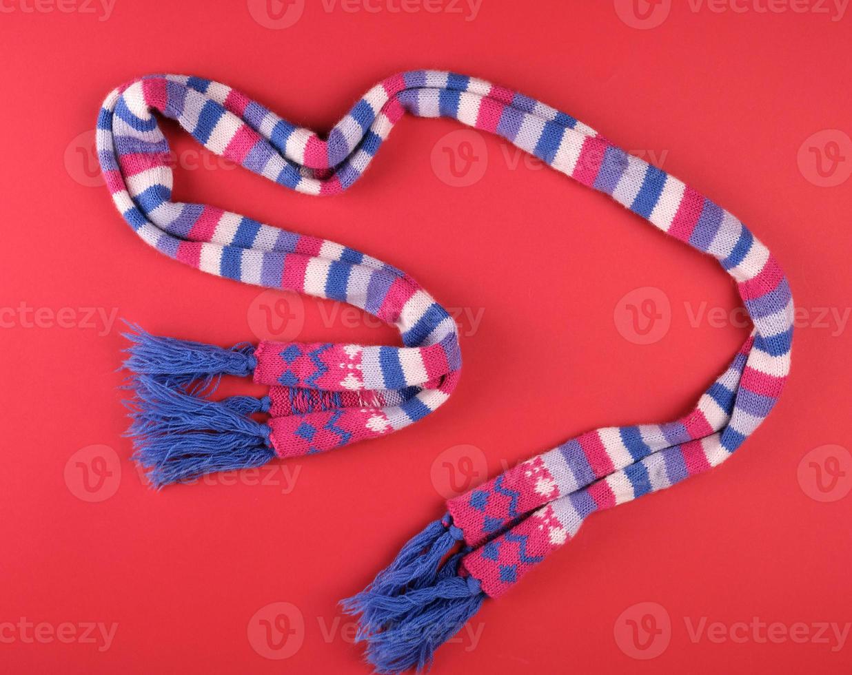 knitted multicolored scarf on a red background photo