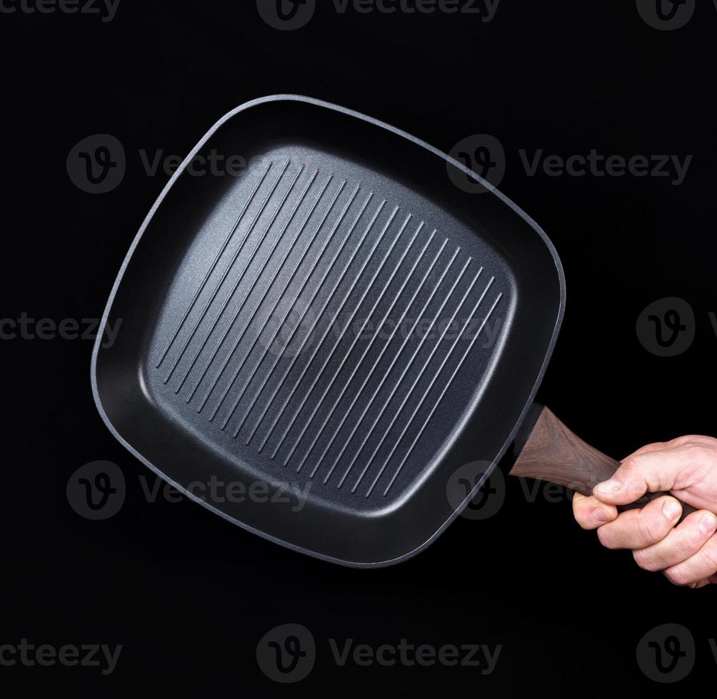 hand is holding a black empty square grill pan photo
