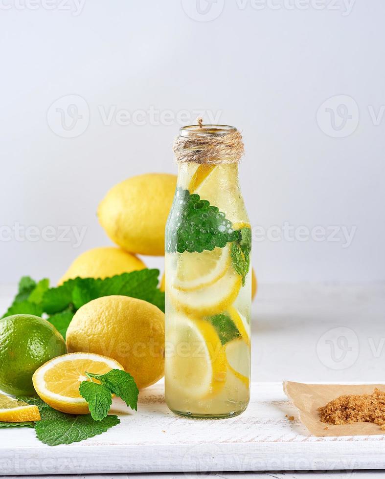 summer refreshing drink lemonade with lemons, mint leaves, lime in a glass bottle photo