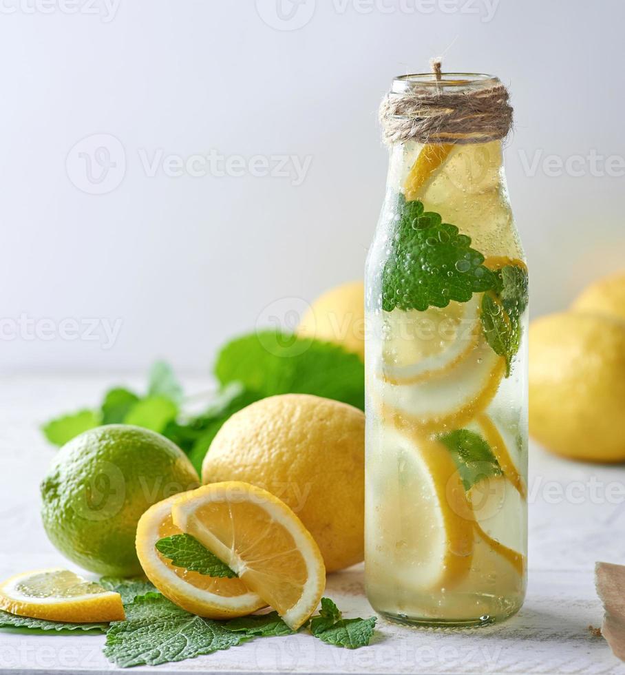 refreshing drink lemonade with lemons, mint leaves, lime in a glass bottle photo