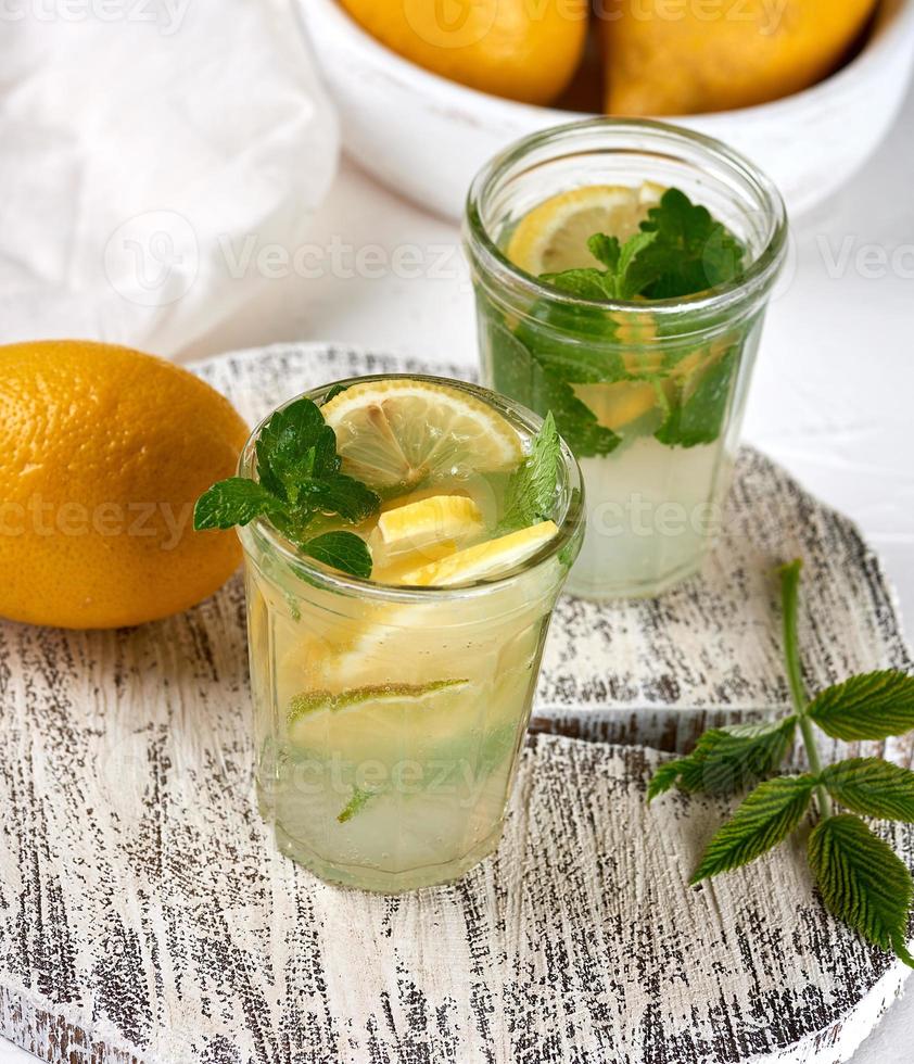 refreshing drink lemonade with lemons, mint leaves, lime in a glass photo