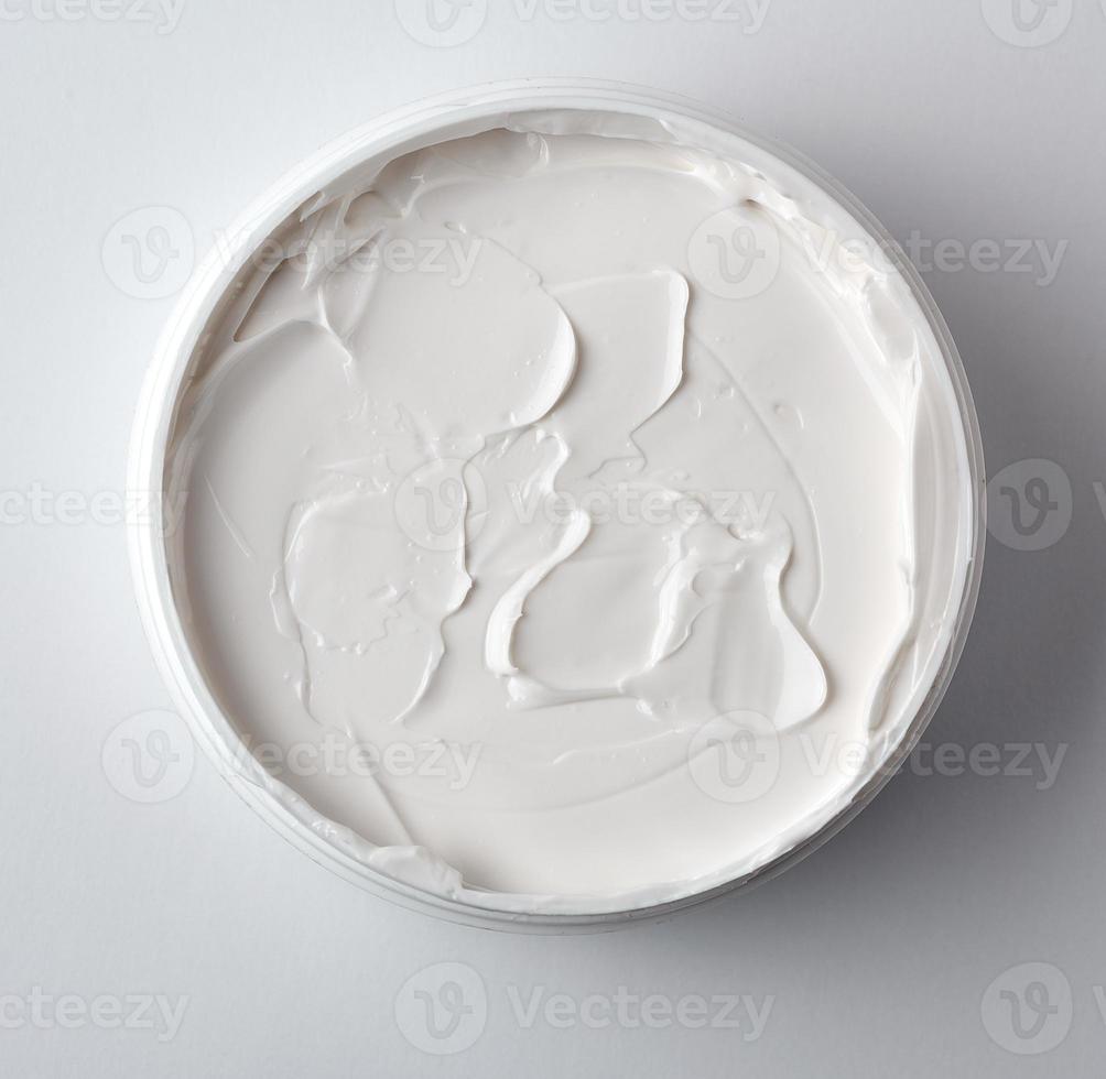 thick white cosmetic cream in a plastic jar, top view photo