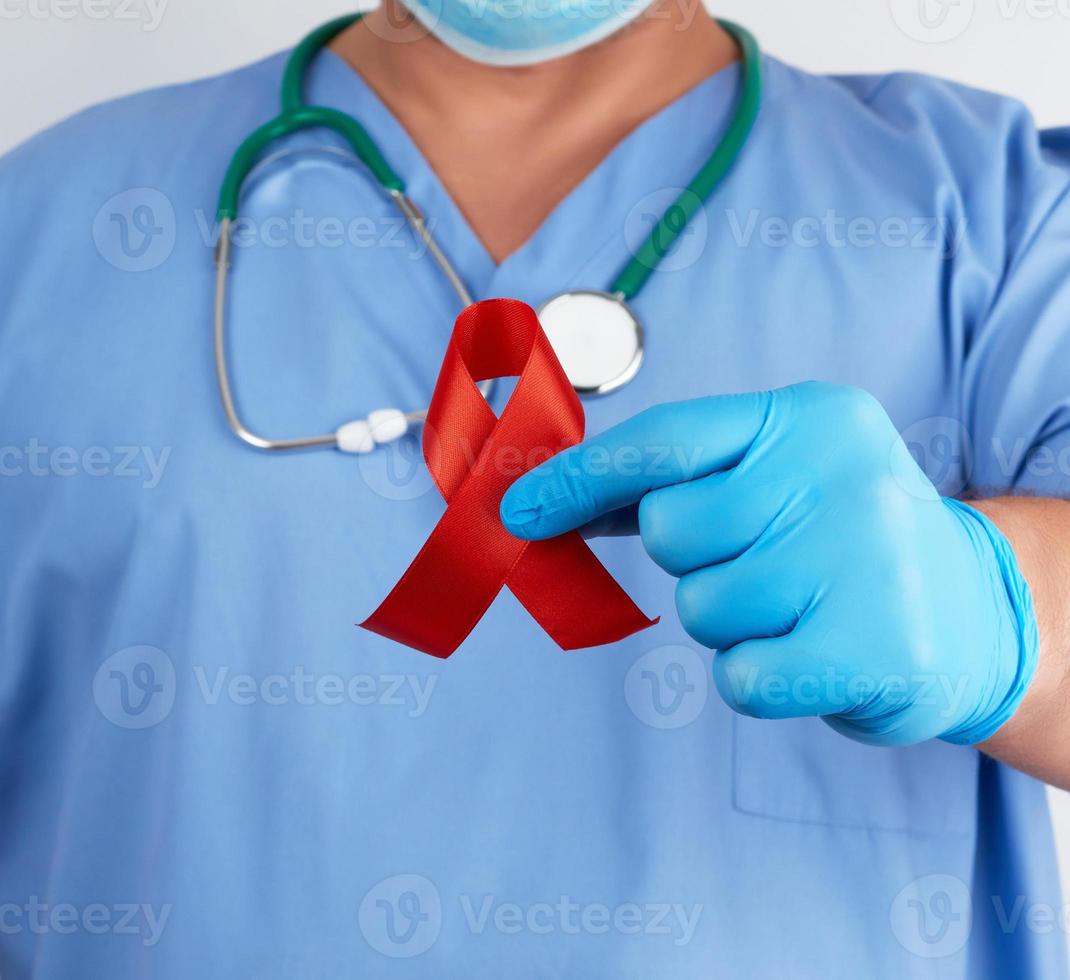 médico con uniforme azul y guantes de látex estériles sostiene una cinta roja foto