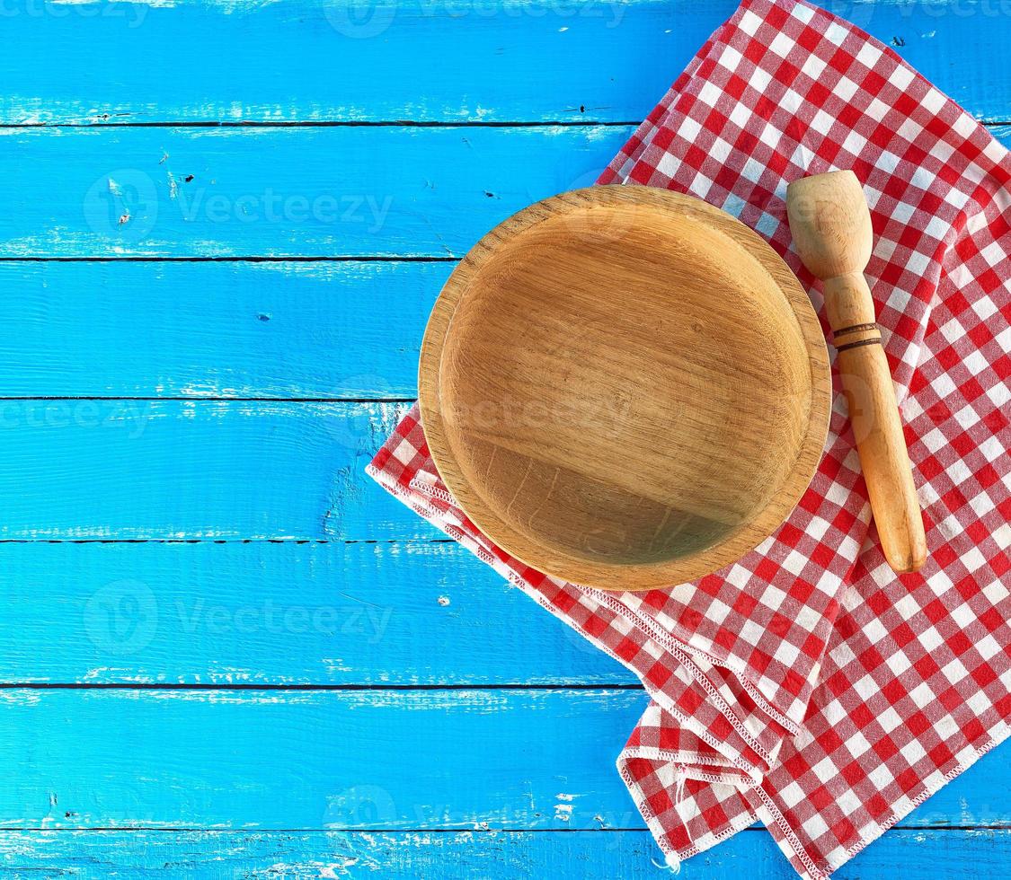 plato de madera redondo vacío y cuchara en una servilleta textil roja-blanca foto