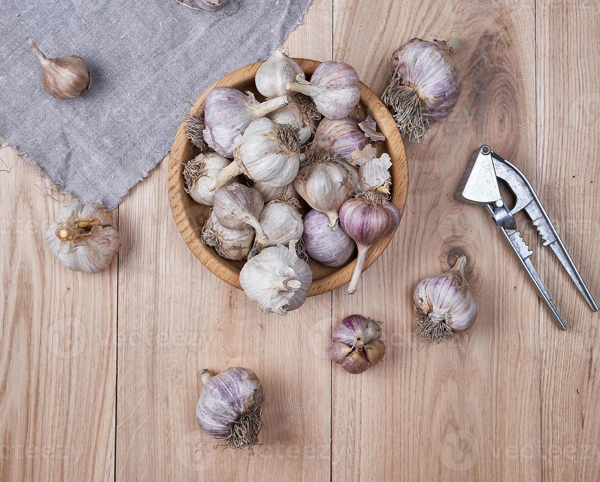 fresh garlic fruits in wooden bowl and an iron press photo