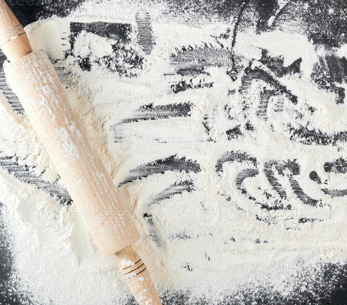 scattered white wheat flour and wooden rolling pin photo