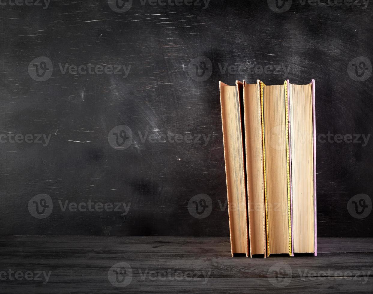 four closed books with yellow sheets on a black chalk board background photo