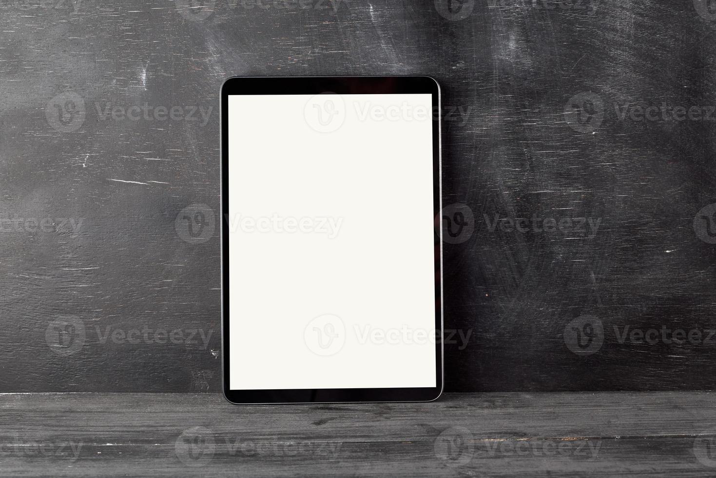 tableta electrónica con una pantalla blanca en blanco contra una pizarra negra foto
