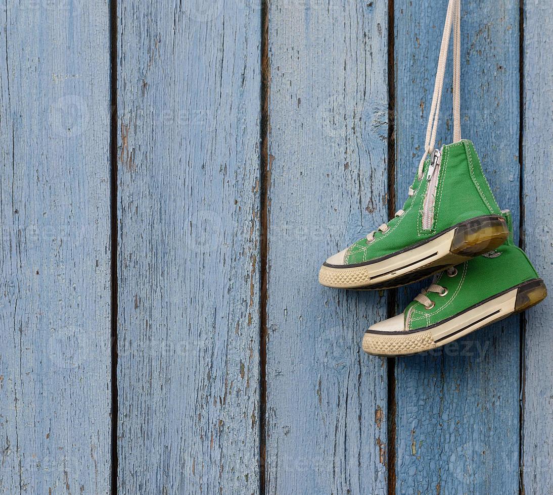 zapatos textiles verdes cuelgan sobre un fondo azul foto