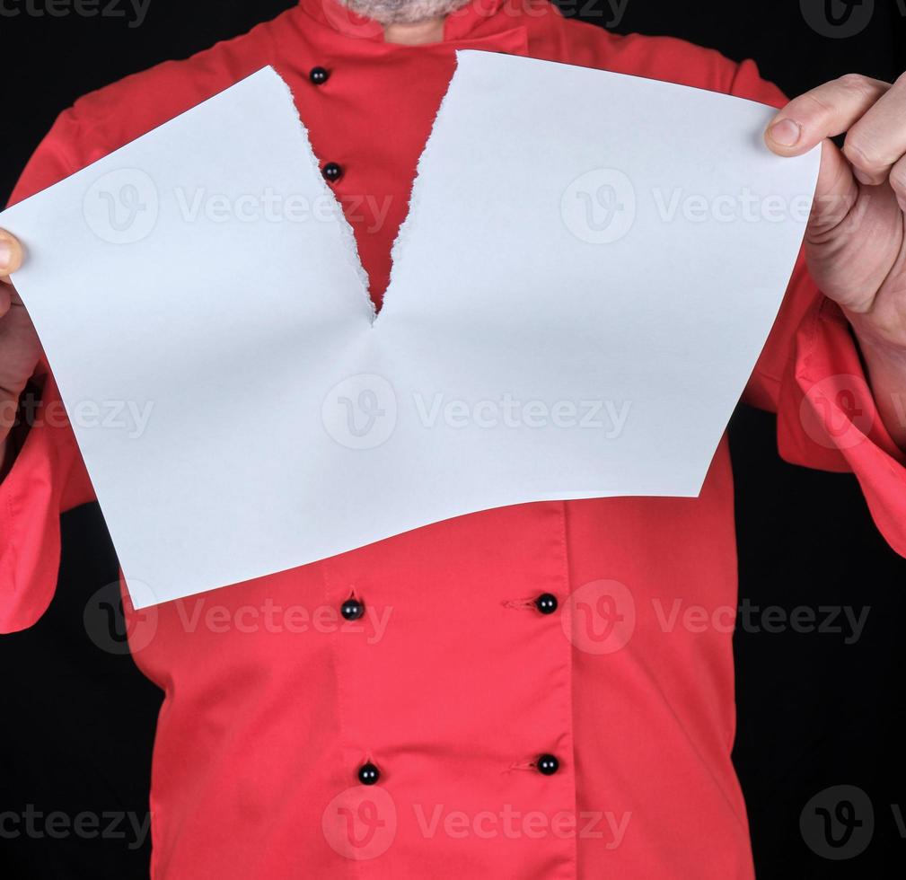 chef in red uniform holding a blank white sheet and tearing it in half photo