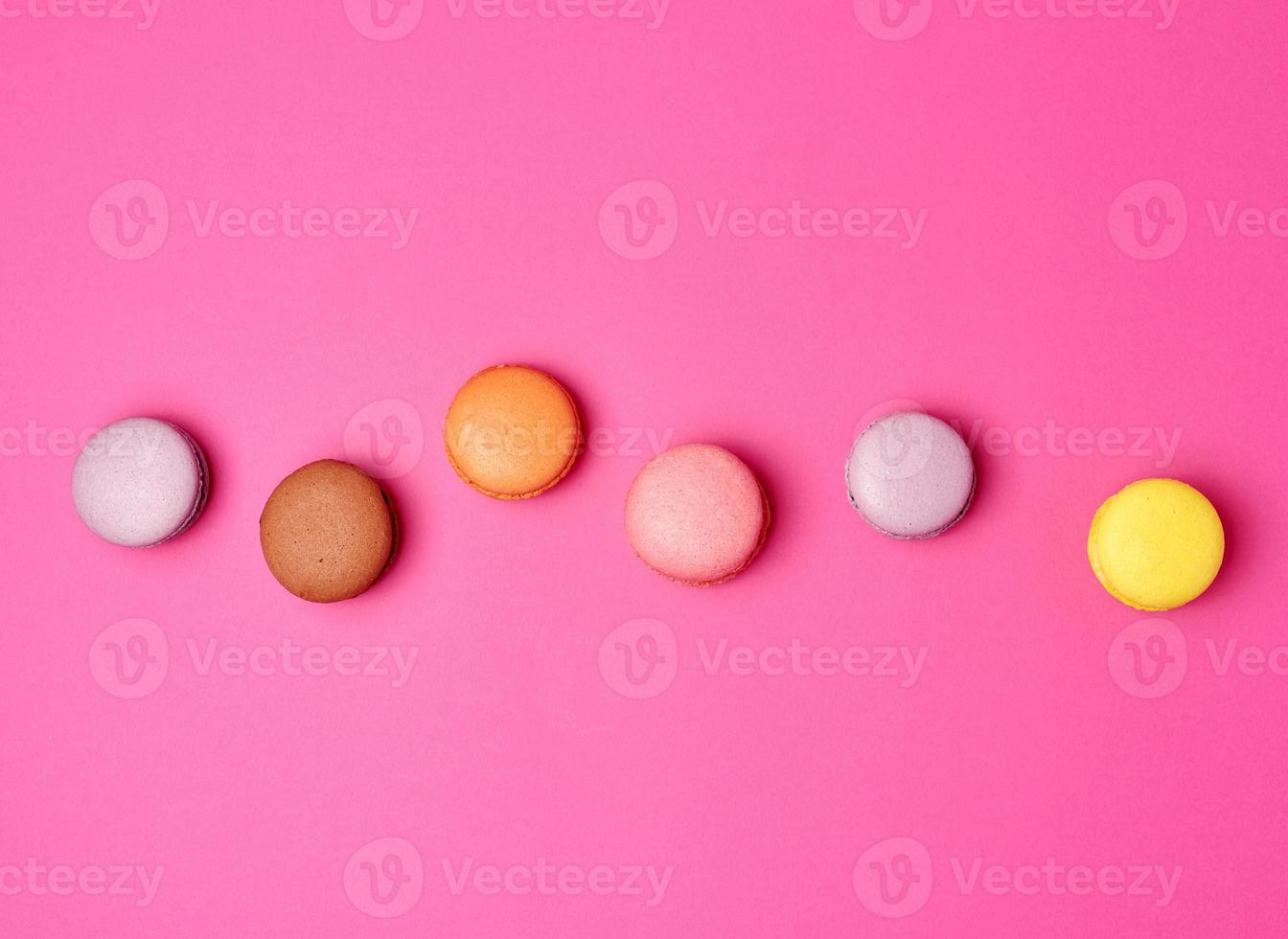 colorful baked macarons almond flour on a pink background photo