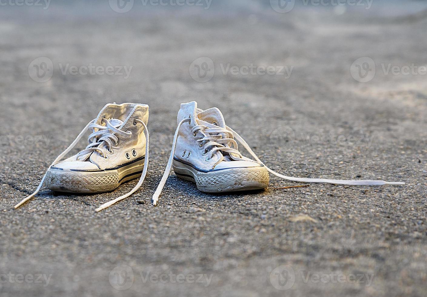 pair of very old white sneakers with untied laces photo