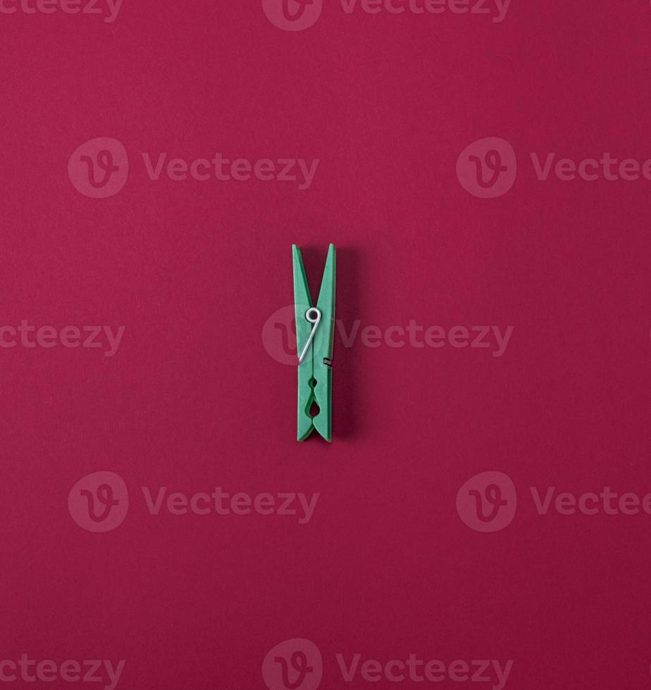 Green plastic clothes pin on a red background photo